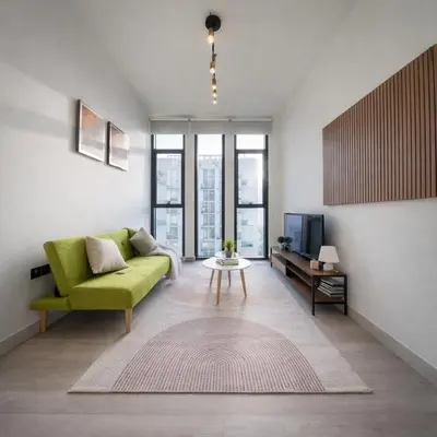a living room with a green couch and a tv at Fully Furnished I Circle Mall I Sleeps 4 in Dubai