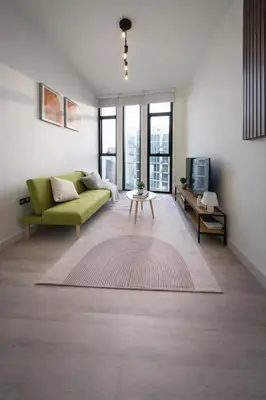 a living room with a green couch and a table at Fully Furnished I Circle Mall I Sleeps 4 in Dubai