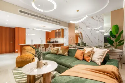 a living room with a green couch and a kitchen at FIRST CLASS 4BR Elegant Beach House Retreat in Dubai