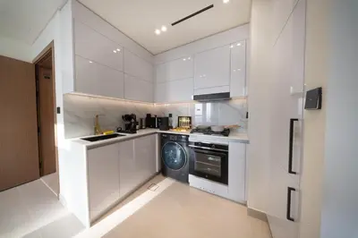 a kitchen with white cabinets and a washing machine at Sleeps 4 I Pool I Circle Mall I Epic Pool in Dubai
