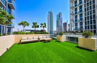 an apartment patio with green grass and a couch at Sleeps 4 I Pool I Circle Mall I Epic Pool in Dubai