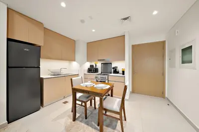a kitchen with a table and chairs and a refrigerator at FIRST CLASS 1BR Creek Beach & Lagoon Escape in Dubai