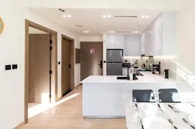 a large kitchen with white counters and chairs at Apartment in Binghatti Crescent, Next to Circle Mall in Dubai