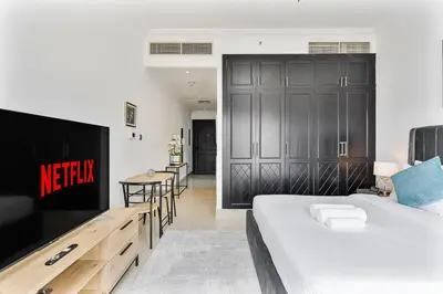 a bedroom with a bed and a table and chairs at Chic Studio in JVC near Butterfly and Miracle Garden in Dubai