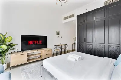 a white bedroom with a tv and a bed at Chic Studio in JVC near Butterfly and Miracle Garden in Dubai
