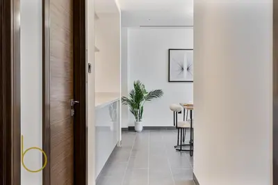 a hallway with a door leading to a dining room at Bookable 2 Bed Crest Sobha Hartland with Burj view in Dubai