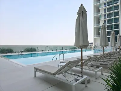 a group of lounge chairs and umbrellas next to a swimming pool at Royalton - Modern JVC Studio Escape in Dubai