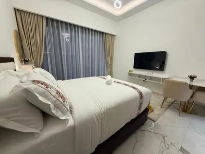 a white bedroom with a bed and a television at Azizi 205 Fully Furnished Apartment in Dubai
