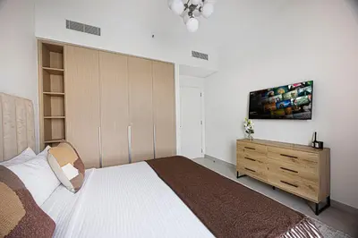 a bedroom with a large bed and a wooden cabinet at Daniels 1BR at Bayshore 4 Creek Beach in Dubai