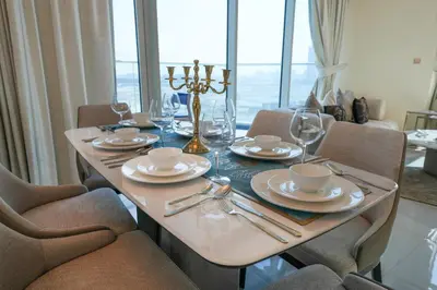 a dining room table with plates and glasses and chairs at EasyGo - Elegant 2 Bedroom near Miracle Garden in Dubai