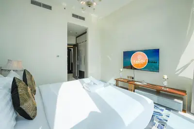 a white bedroom with a bed and a tv at EasyGo - Elegant 2 Bedroom near Miracle Garden in Dubai