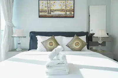 a bedroom with a white bed with towels on it at EasyGo - Elegant 2 Bedroom near Miracle Garden in Dubai