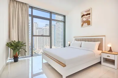 a white bedroom with a large white bed and a large window at Beach Vista - Stunning Sea View in Dubai