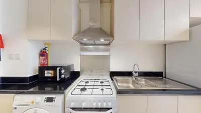 a white kitchen with a stove and a sink at Vacationer I Luxury Studio I Scenic Golf Course & Skyline Views I Carson B Tower in Dubai Marina