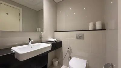 a white bathroom with a sink and a toilet at DAMAC - Bays Edge 1BR - Burj Khalifa Views & Pool in Dubai