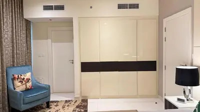 a room with a blue chair and a wall at DAMAC - Bays Edge 1BR - Burj Khalifa Views & Pool in Dubai