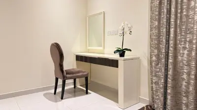 a chair sitting next to a vanity with a mirror at DAMAC - Bays Edge 1BR - Burj Khalifa Views & Pool in Dubai