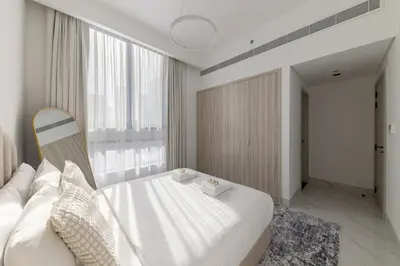a bedroom with a white bed and a large window at Brand New Grand 2BR Duplex apartment in Jumeirah Village Circle with Pool, Gym and kids playground in Dubai