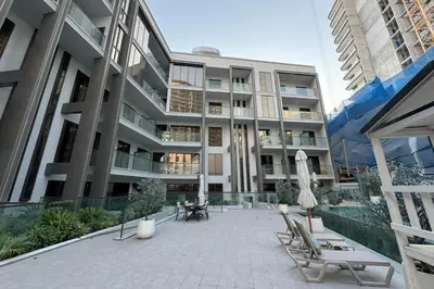 an apartment building with chairs and umbrellas in a courtyard at Brand New Grand 2BR Duplex apartment in Jumeirah Village Circle with Pool, Gym and kids playground in Dubai