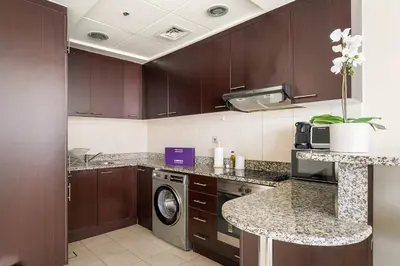 a kitchen with wooden cabinets and a washer and dryer at Silkhaus Luxurious 1BR at Sky Gardens in DIFC in Dubai