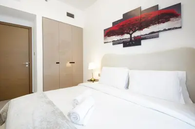 a white bedroom with a large white bed with two pillows at Spacious 2BR in Missoni - Canal Views - Near Metro in Dubai