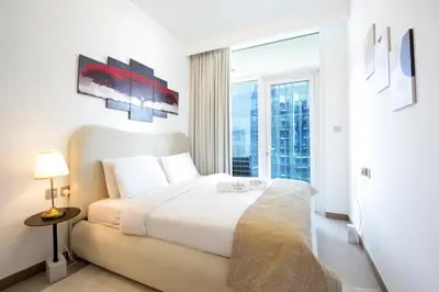 a white bedroom with a bed and a large window at Spacious 2BR in Missoni - Canal Views - Near Metro in Dubai