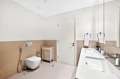 a bathroom with a toilet and two sinks and a mirror at New 3BD in Grove Creek Beach with Stunning View in Dubai