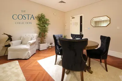 a room with a table and chairs and a couch at Water Edge 2BR - Panoramic 360 Canal View in Dubai