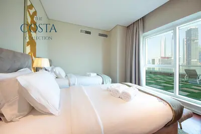 a hotel room with two beds and a window at Water Edge 2BR - Panoramic 360 Canal View in Dubai