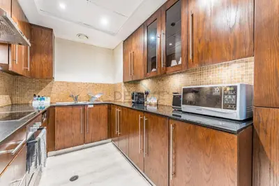 a kitchen with wooden cabinets and a microwave at 1BR Near Burj Khalifa and Dubai Mall, Easy Access to Dubai Marina and Palm Jumeirah by Road or Metro, BLVD Walk, Downtown Dubai by Deluxe Holiday Homes in Dubai