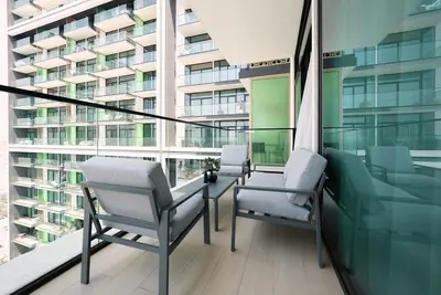 two chairs and a table on a balcony with a building at JVC - Designer 2 BHK apartment - Pool&Gym - by MKB LIVING in Dubai