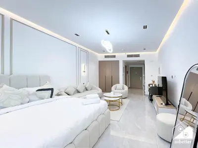 a white bedroom with a large bed and a living room at Relaxing ST Getaway l Balcony, Pool & Gym Access in Dubai