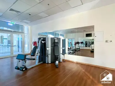 a gym with cardio equipment in a large room with wood floors at Relaxing ST Getaway l Balcony, Pool & Gym Access in Dubai