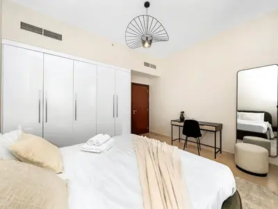 a bedroom with a large white bed and a desk at Jumeirah Beachfront with Ain View and Sea View 2BR in Dubai