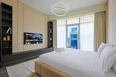 a bedroom with a large white bed and a tv at Modern Sophistication with Stunning City Views in Dubai