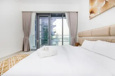 a bedroom with a large white bed and a window at Cozy 2BR APT With Canal Views, Pool with Burj View in Dubai