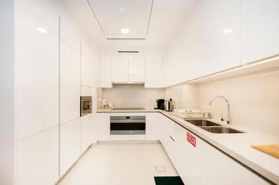 a white kitchen with white cabinets and a sink at Cozy 2BR APT With Canal Views, Pool with Burj View in Dubai