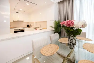 a kitchen with a glass table with a vase of flowers at Cozy 2BR APT With Canal Views, Pool with Burj View in Dubai