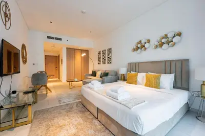 a bedroom with a large bed and a living room at TRPS - Marquise Square, Business Bay - Burj Khalifa View, Spacious Studio, Fully Furnished in Dubai
