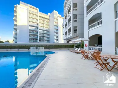 a swimming pool with tables and chairs and buildings at Elegant Studio with Balcony & Full Amenities in Dubai