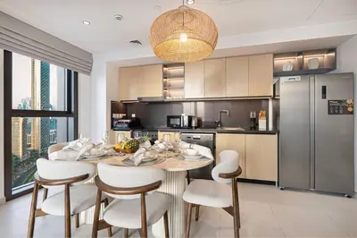 a kitchen with a table and chairs and a refrigerator at Mahogany 18 - 2BR 10 Guests - Walk to Dubai Mall in Dubai