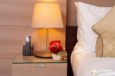 a hotel room with a bed and a phone and flowers at Suitestay-Fahion Avenue Dubai mall in Dubai
