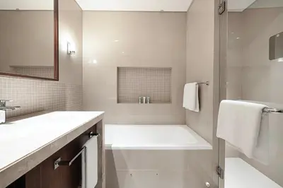 a white bathroom with a tub and a sink at Skyline Aura 1 & 2 Bedroom Apartments I Burj Khalifa & Fountain Views I Dubai Mall Access I Parking, Gym, Wi-Fi & Infinity Pool in Dubai
