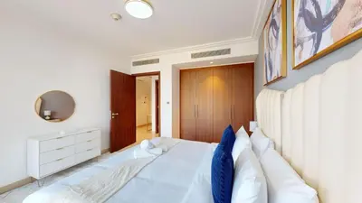 a bedroom with a large white bed with blue pillows at Skyline Aura 1 & 2 Bedroom Apartments I Burj Khalifa & Fountain Views I Dubai Mall Access I Parking, Gym, Wi-Fi & Infinity Pool in Dubai