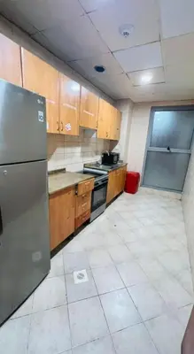 a kitchen with wooden cabinets and a stainless steel refrigerator at Private Double Room In Barsha Heights Near Metro in Dubai