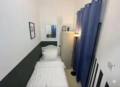 a small room with a bed and a blue curtain at The White Haven Room in Tecom Barsha Heights in Dubai