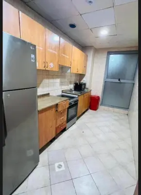 a kitchen with wooden cabinets and a stainless steel refrigerator at The White Haven Room in Tecom Barsha Heights in Dubai