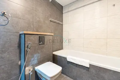 a bathroom with a tub and a toilet and a shower at Balcony Overlooking the Community, Quick Metro Access,Short 15-Minute Drive to Ibn Battuta Mall, Viktoria Residency, Al Furjan by Deluxe Holiday Homes in Dubai