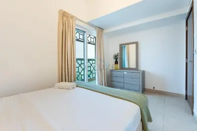 a bedroom with a white bed and a window at Balcony Overlooking the Community, Quick Metro Access,Short 15-Minute Drive to Ibn Battuta Mall, Viktoria Residency, Al Furjan by Deluxe Holiday Homes in Dubai