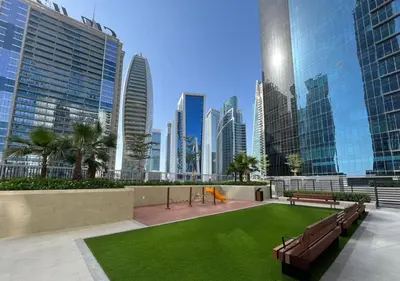 a park with benches and grass in a city at Stylish 1-Bedroom with Lake View in Business Bay in Dubai
